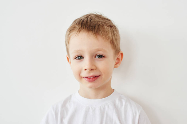 Portrait of little boy in white t-shirt looking at camera and posing on white studio background - Zdjęcie, obraz