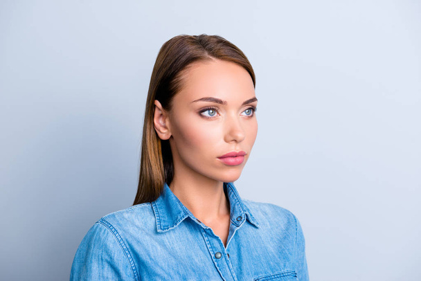 Portrait of half turned serious woman in jeans shirt with concentrated thoughtful expression isolated on grey background - Foto, afbeelding