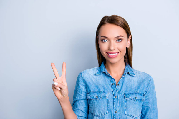 Portrait of  nice cute girl in casual outfit jeans shirt showing v-sign having beaming smile, standing over grey background - Foto, afbeelding