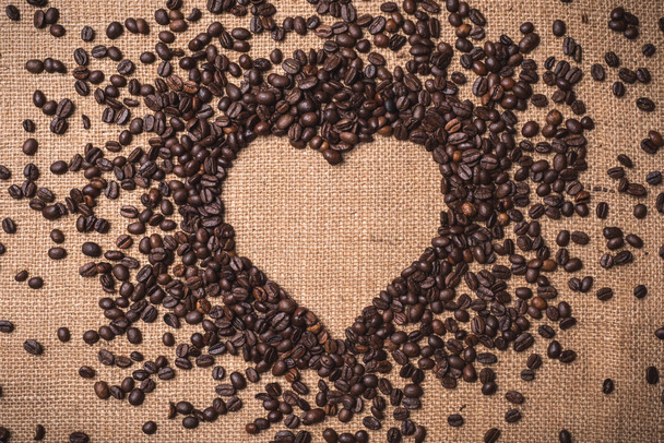 το Top view καρδιά σχήμα κόκκων καφέ σε εξουσιοδοτημένους τους juta κλωστοϋφαντουργίας - Φωτογραφία, εικόνα