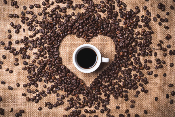 το Top view καρδιά σχήμα κόκκων καφέ σε εξουσιοδοτημένους τους juta κλωστοϋφαντουργίας - Φωτογραφία, εικόνα