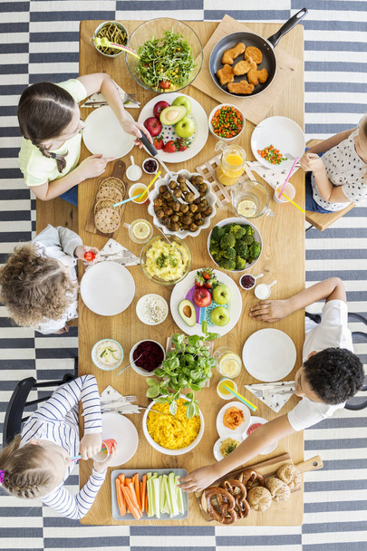 Vista dall'alto sui bambini che mangiano una cena sana a tavola durante la festa di compleanno
 - Foto, immagini