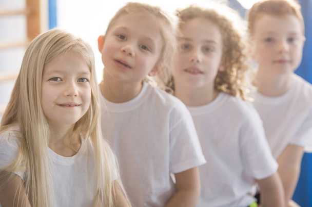 Крупный план улыбающейся блондинки с друзьями в школьном спортзале
 - Фото, изображение
