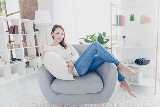 Portrait of pretty charming girl  sitting on armchair in modern livingroom looking at camera enjoying new cozy apartment - Zdjęcie, obraz