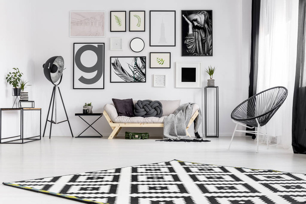 Black armchair near sofa in modern living room interior with gallery of posters on the wall - Foto, immagini