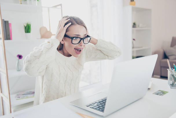 Portrait of sad upset woman in glasses yelling looking at screen of computer holding hands on head having panic big problem sitting in workplace workstation - Foto, Imagen