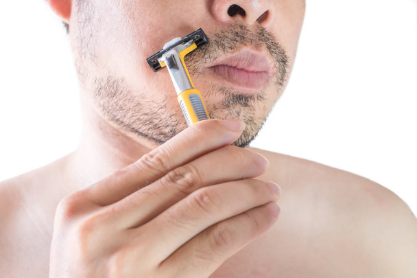 Asian young man using a razor shaving his beard. Do not use cream. on white background and clipping path. Clean face treatment concept. - Foto, Bild