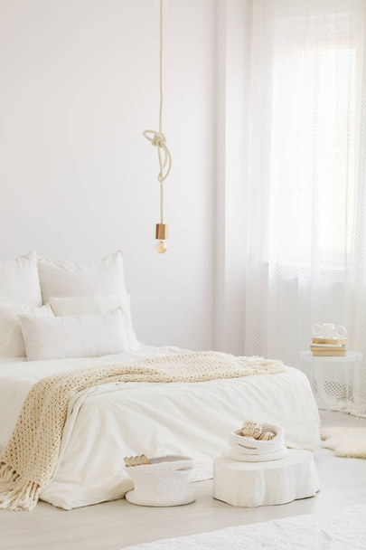 Bright scandinavian bedroom interior with white bedding, woolen blanket and long curtain - Foto, Imagen