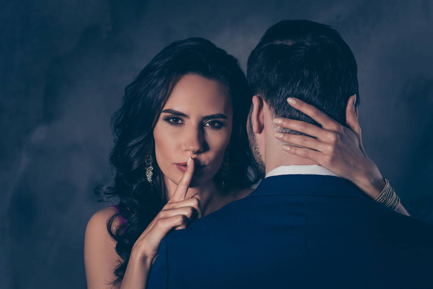 Shh! Portrait of tempting brunette lady showing silence sign with forefinger touching secret mysterious gentlemen with rear view, lovely Mr and Mrs isolated on grey background - Fotografie, Obrázek