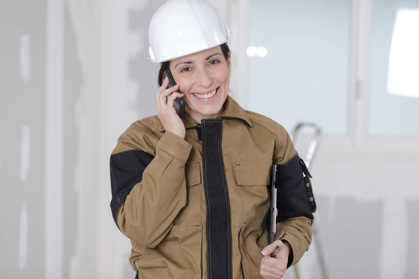 happy female construction organizer on the phone with male workers - 写真・画像