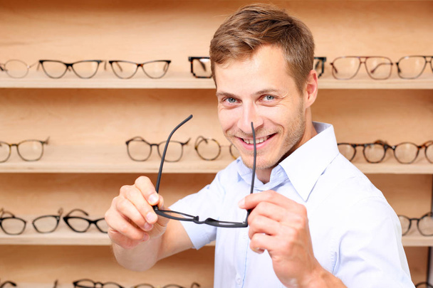 Facial glasses. The man chooses spectacle frames in the optical salon - Foto, Bild