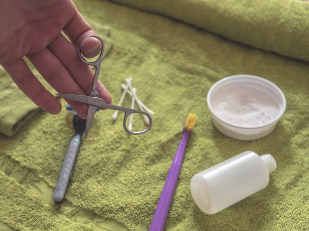 hand holding nail scissors above the towel with personal hygiene products - Photo, Image