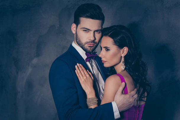 Portrait of lovely romantic couple embracing, pretty charming mrs with bijoutery, rich virile mr with bristle in tuxedo with bow isolated on grey background - Foto, Imagem