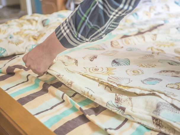 hands making a new bed with beautiful blanket in bedromm - 写真・画像