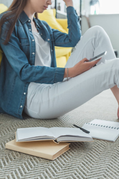cropped shot of girl using smartphone while studying at home - Foto, Imagem