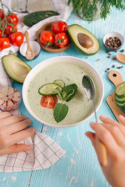 Woman eating cream of avocado soup with cucumbers and tomatoes  - Photo, Image