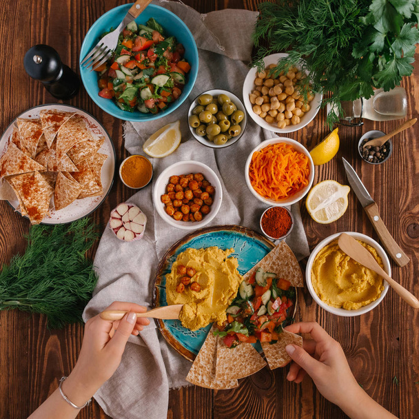 Widok z góry kobiecych rąk i hummus serwowane z warzywami i pita  - Zdjęcie, obraz