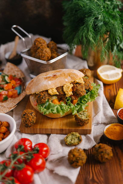 Frischer veganer Burger mit Falafel-Bällchen, Hummus und Gemüse - Foto, Bild