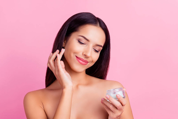 Charming, pretty, attractive, nice, cute woman  applying face cream for problem, combined skin, holding bank with lotion, isolated on pink background - Zdjęcie, obraz