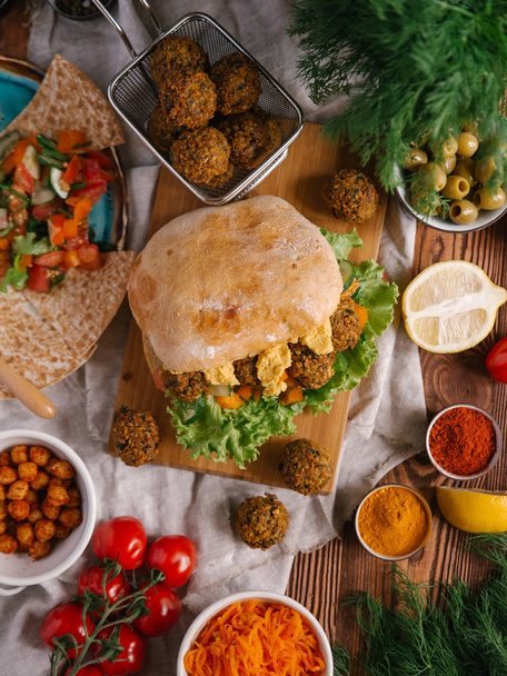 Frischer veganer Burger mit Falafel-Bällchen, Hummus und Gemüse - Foto, Bild