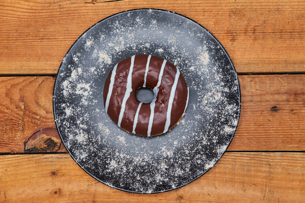 Appetizing chocolate donut with sprinkles lie on a wooden board background. - Foto, Bild