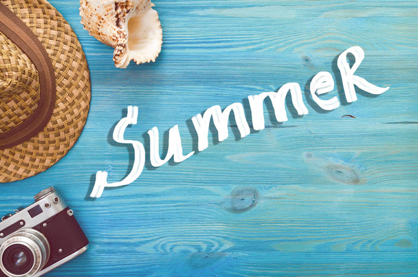 Summer background with copy space. Retro photo camera, seashell and hat on blue wooden background. - Foto, Imagem