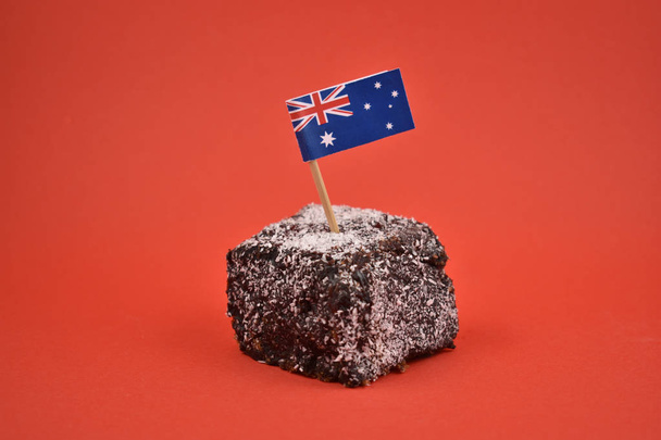 Lamington stock images. Lamington on a red background. Australian sweet delicacy. Important day. Lamington Day background. Australian cake with flag - Photo, Image