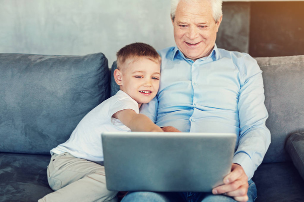 Happy boy showing his grandpa a new laptop - Foto, afbeelding