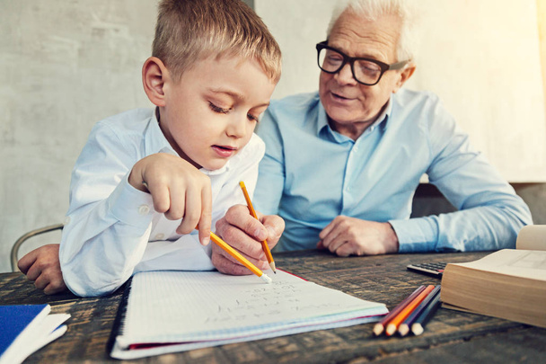 Attentive pupil doing homework with his grandfather - Foto, immagini