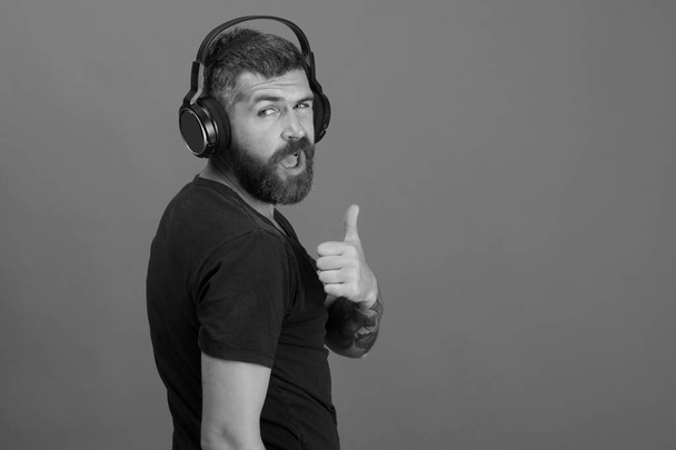 Music and leisure concept. Dj with beard wears headphones - 写真・画像