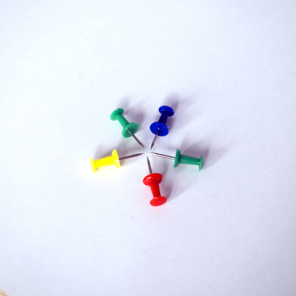 Vijf kleurrijke pushpins zijn gerangschikt rond en kijken naar elkaar - Foto, afbeelding