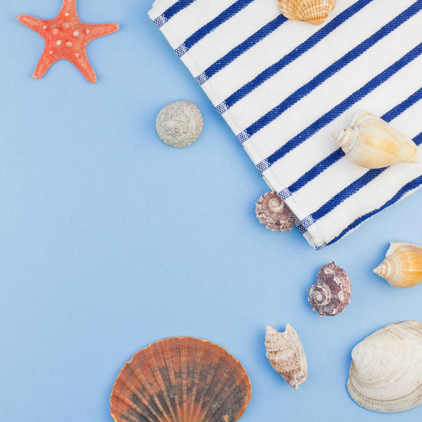 Creative square flat lay concept of summer travel vacations. Top view of beach towel and seashells and starfish on pastel blue background with copy space in minimal style, template for text - Photo, Image