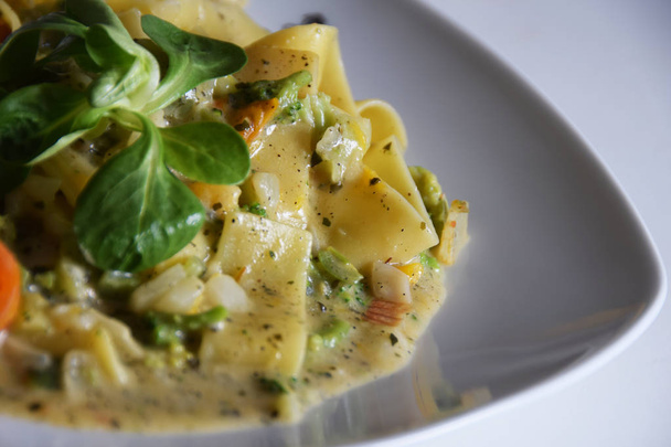 tagliatelle pasta with vegetables, cream-herb sauce, tomatoes - Foto, afbeelding