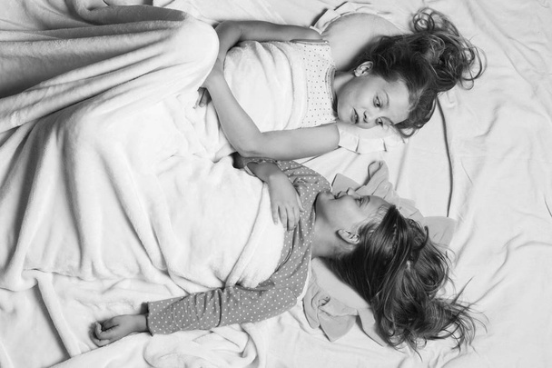 Schoolgirls have rest in bed looking at each other. - Fotoğraf, Görsel