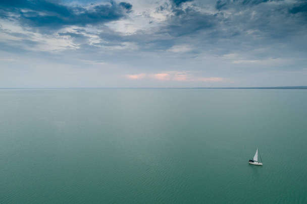 weißes Segelboot auf dem Balaton mit wolkenverhangenem Himmel - Foto, Bild