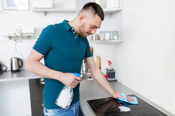 man with rag cleaning cooker at home kitchen - Foto, Bild