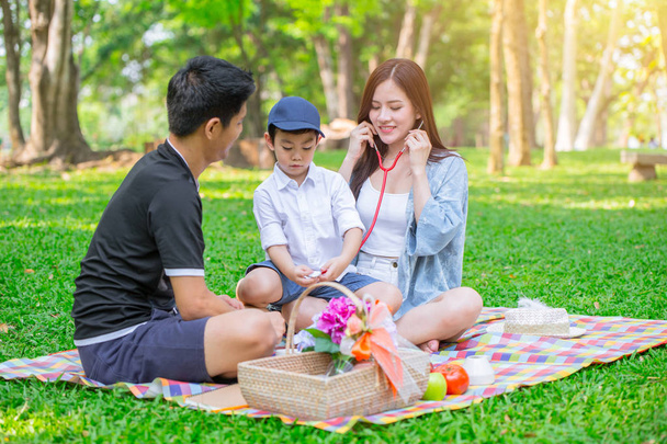 アジア 10 代家族 1 人の子供幸せな休日ピクニック瞬間再生の役割公園で医師として. - 写真・画像