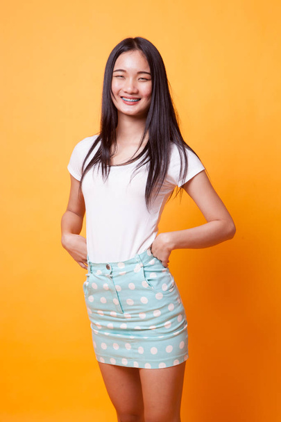 Portrait of beautiful young Asian woman on bright yellow background - Photo, Image