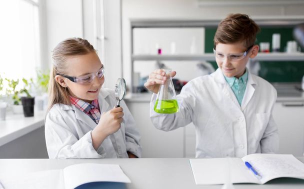lapset, joilla on pullo ja suurennuslasi kemian luokassa
 - Valokuva, kuva