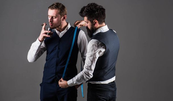 Man with beard holds measuring tape. Tailor taking measurements - 写真・画像