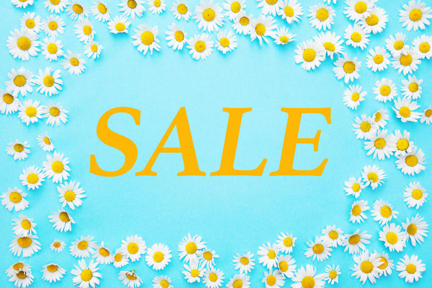 Sale written on blue background framed with white daisies - Foto, Bild