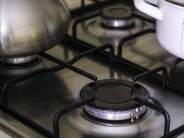 The image of a gas stove close up with kettle and pan - Fotó, kép
