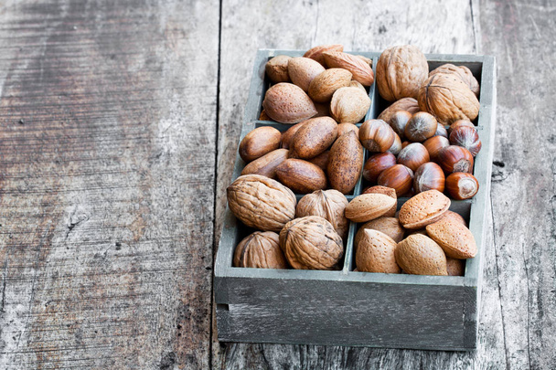 Various  nuts in wooden box on rustic table  - Photo, Image