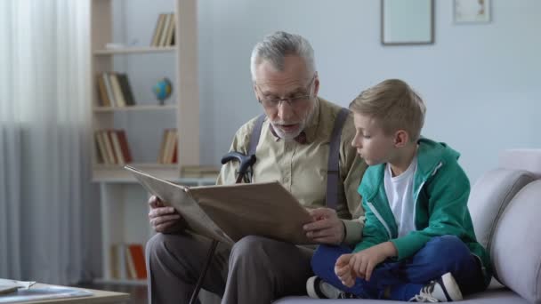 Old man reading book aloud to grandson, giving experience to younger generation - Filmagem, Vídeo
