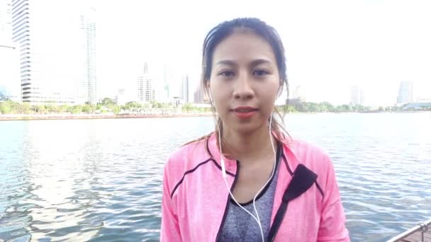 Αργή κίνηση - όμορφη γυναίκα της Ασίας σε ρούχα γυμναστικής χρησιμοποιούν ένα smartwatch για να ακούσετε μουσική, μιλώντας στο τηλέφωνο μετά το τρέξιμο στο πάρκο. Ελκυστική υγιείς γυναίκες τζόκινγκ.  - Πλάνα, βίντεο