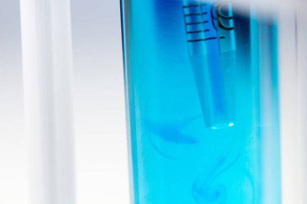研究室で青い液体の水を試験管にピペットします。. - 写真・画像
