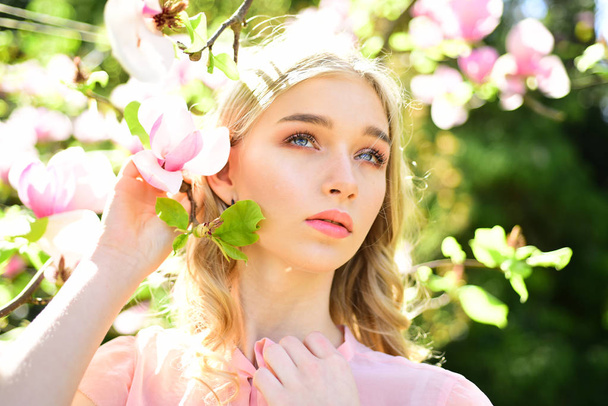 girl smell pink magnolia flowers sunny spring. girl with beautiful magnolia flower - Fotoğraf, Görsel