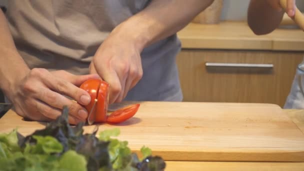 Woman hands cutting tomato in the kitchen. Beautiful happy asian couple are cooking in the kitchen. Young asian couple have romantic time while staying at home. Couple lifestyle at home concept. - Séquence, vidéo