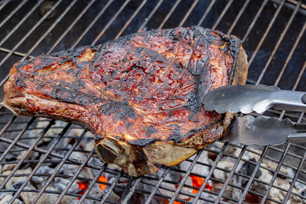 Zbliżenie żebra wołowiny z grilla na grilla złowionych z specjalne szczypce - Zdjęcie, obraz