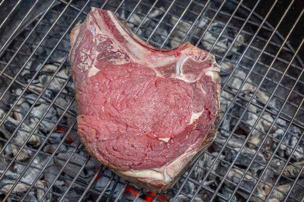 Close-up top view of a raw beef rib on a barbecue grill - Photo, Image